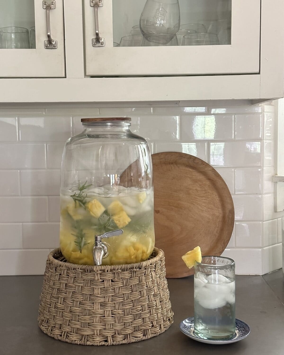 beverage jar on woven stand with pineapple rosemary water