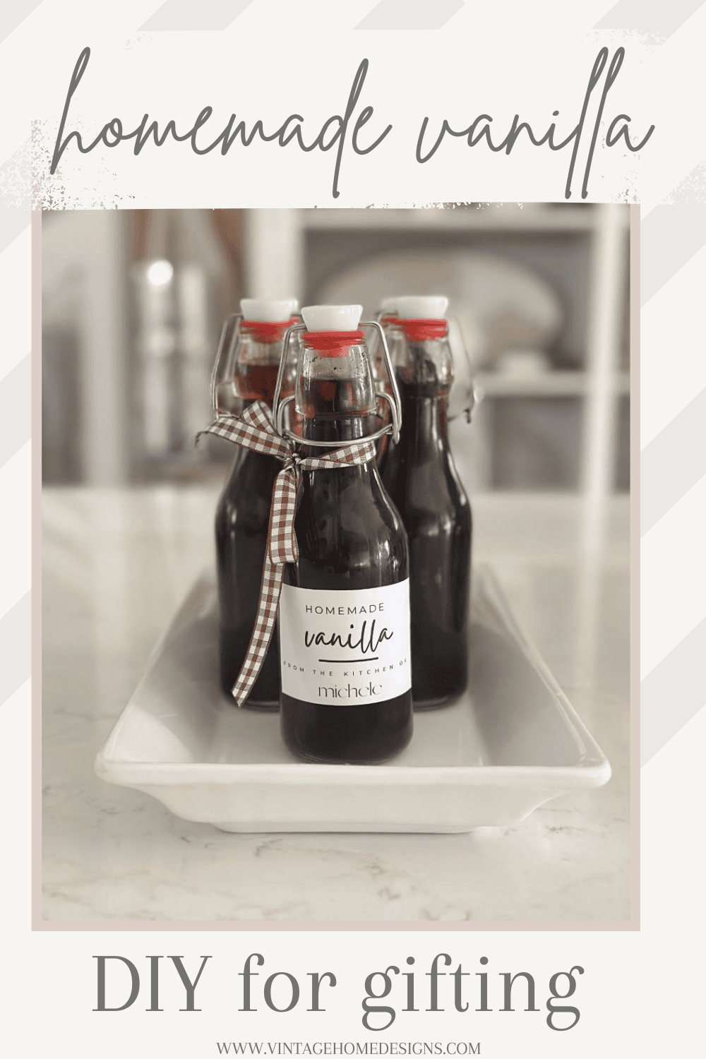 Three glass bottles filled with Easy Homemade Vanilla Extract DIY, labeled and sealed with red-capped lids, are displayed on a white tray. One bottle, tied with a gingham ribbon, highlights this thoughtful “DIY for gifting” idea.